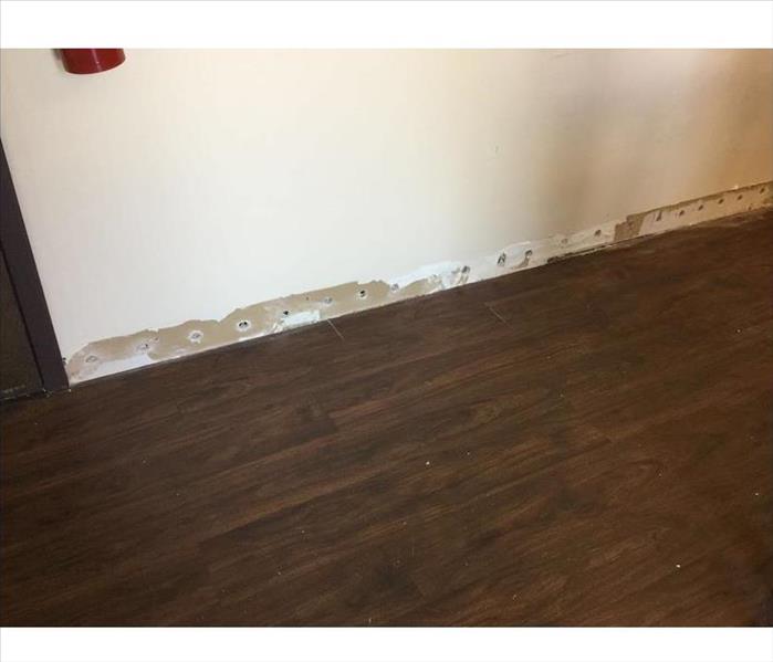Room with hardwood flooring and weep holes in sheetrock