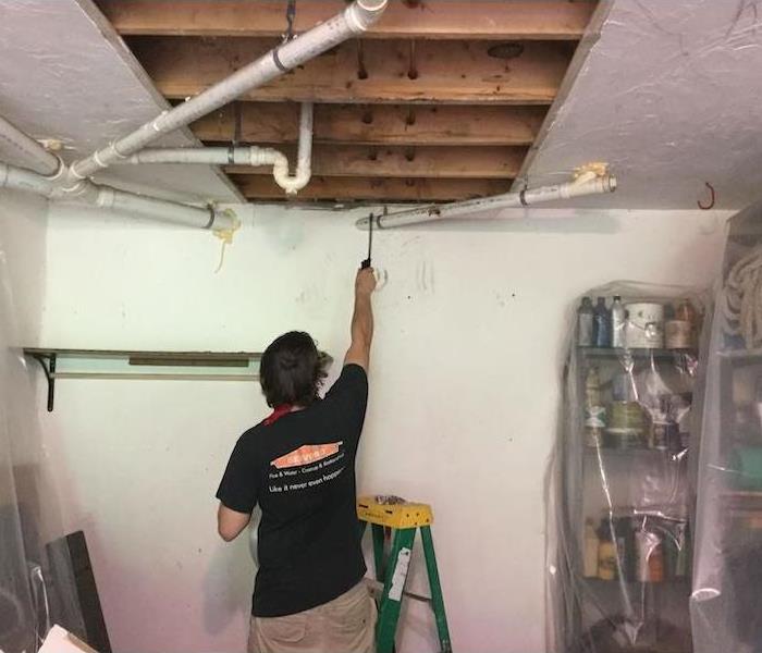 SERVPRO tech in room with the ceiling cut open