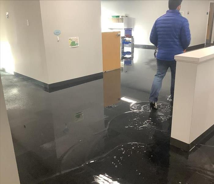 Initial visit technician walking through a water-saturated commercial carpet with standing water