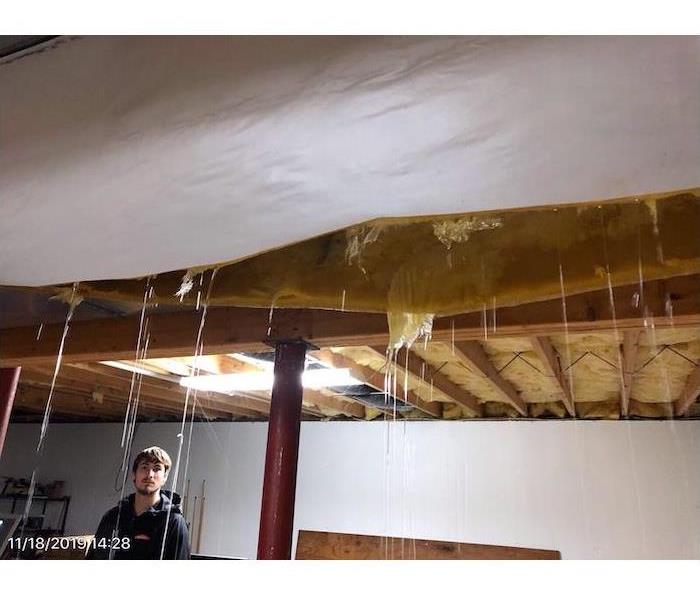 Basement ceiling with man watching water dripping through